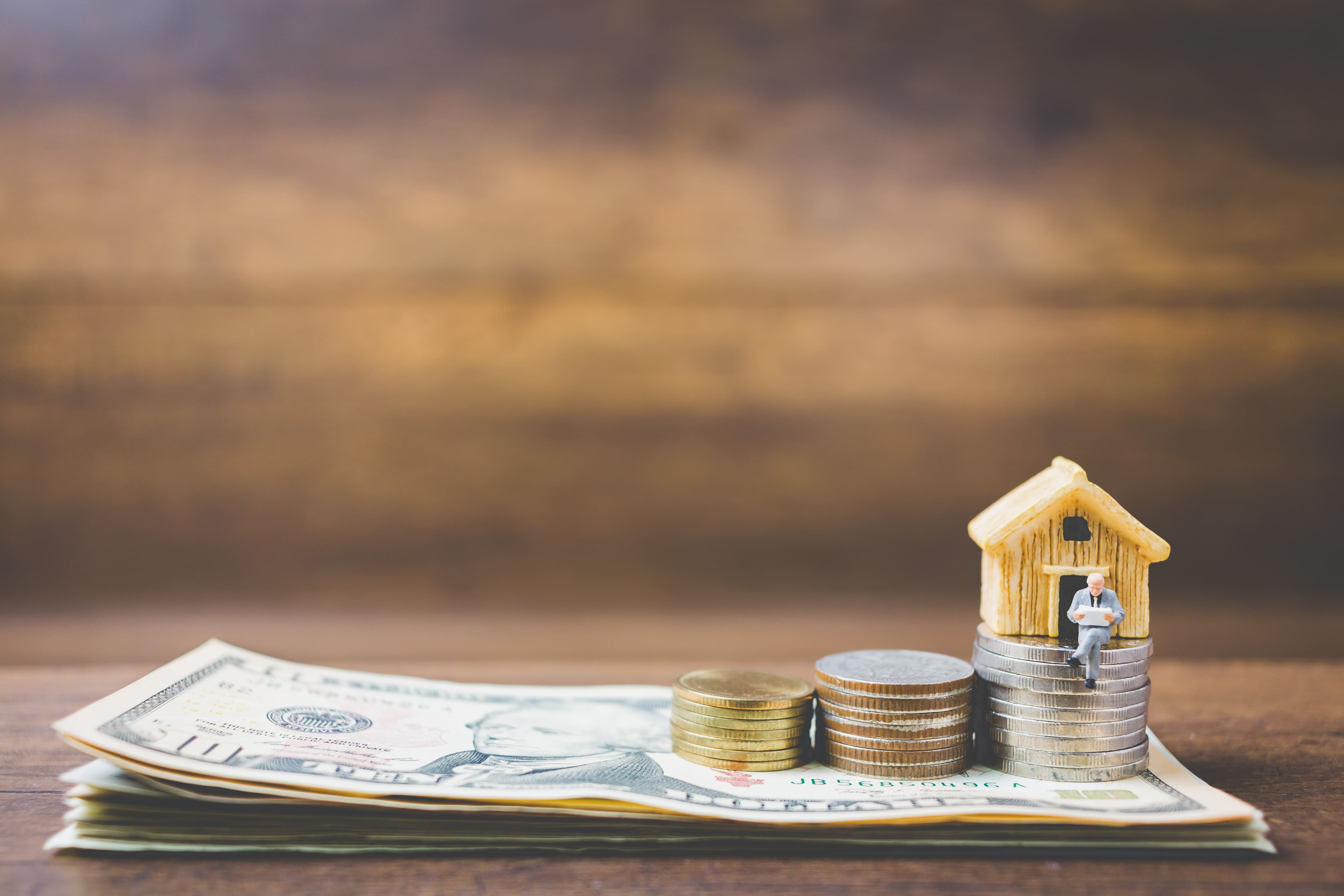 Investor figure on a property model with cash representing passive income