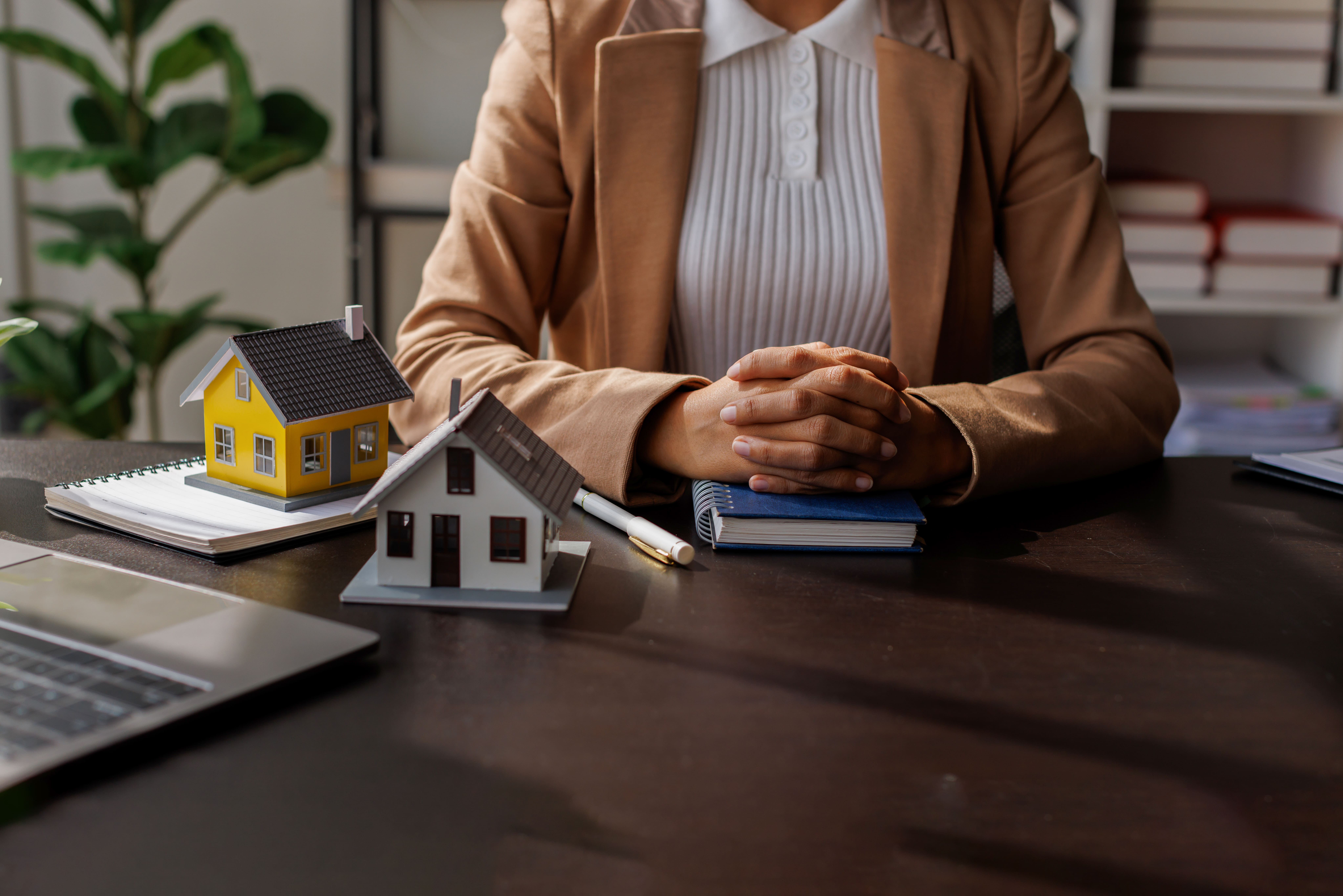 Real estate advisor at a desk with multiple house models for consultation