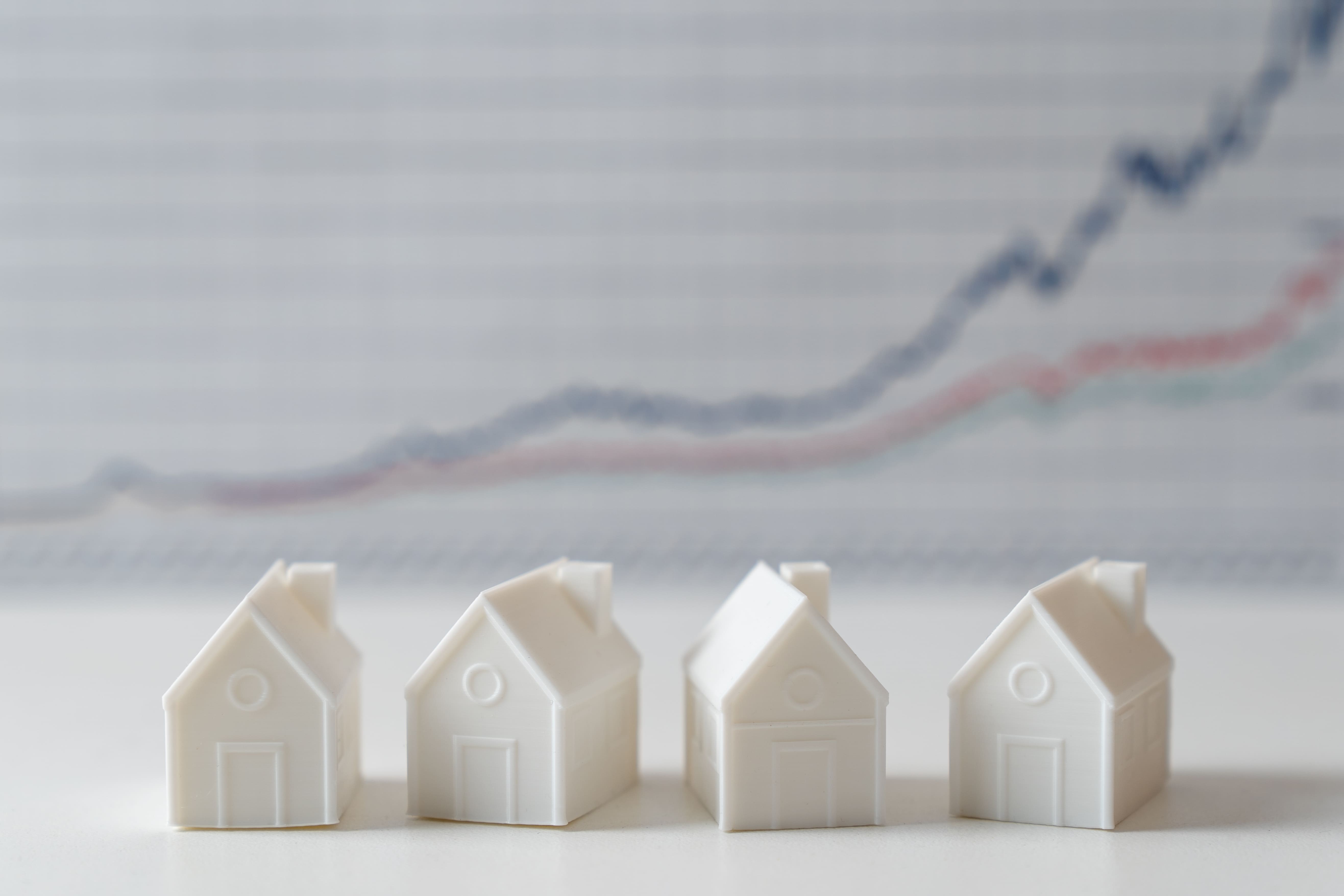 Rising graph with house model showing housing market price increases