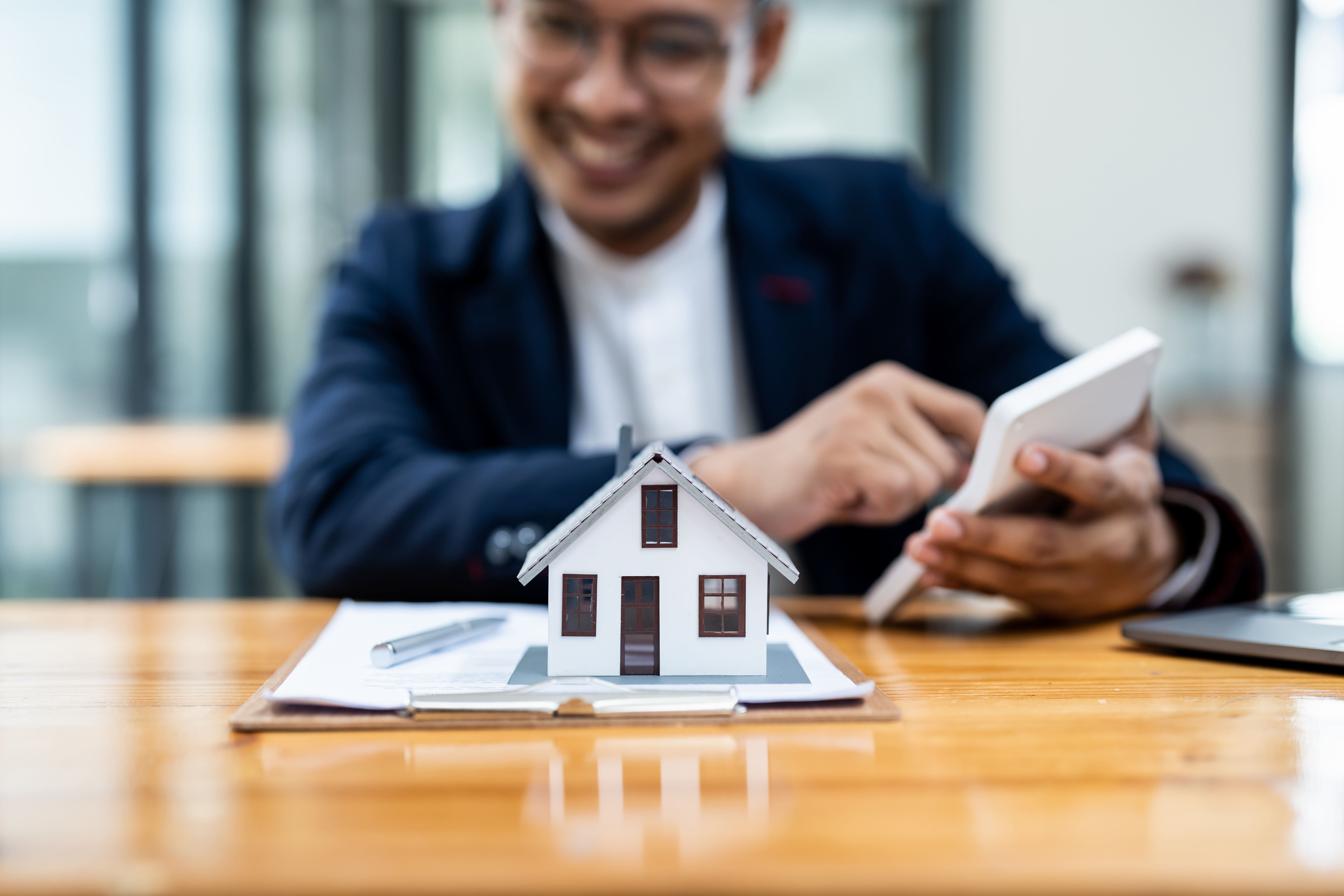 Professional on a call with a house model on the desk
