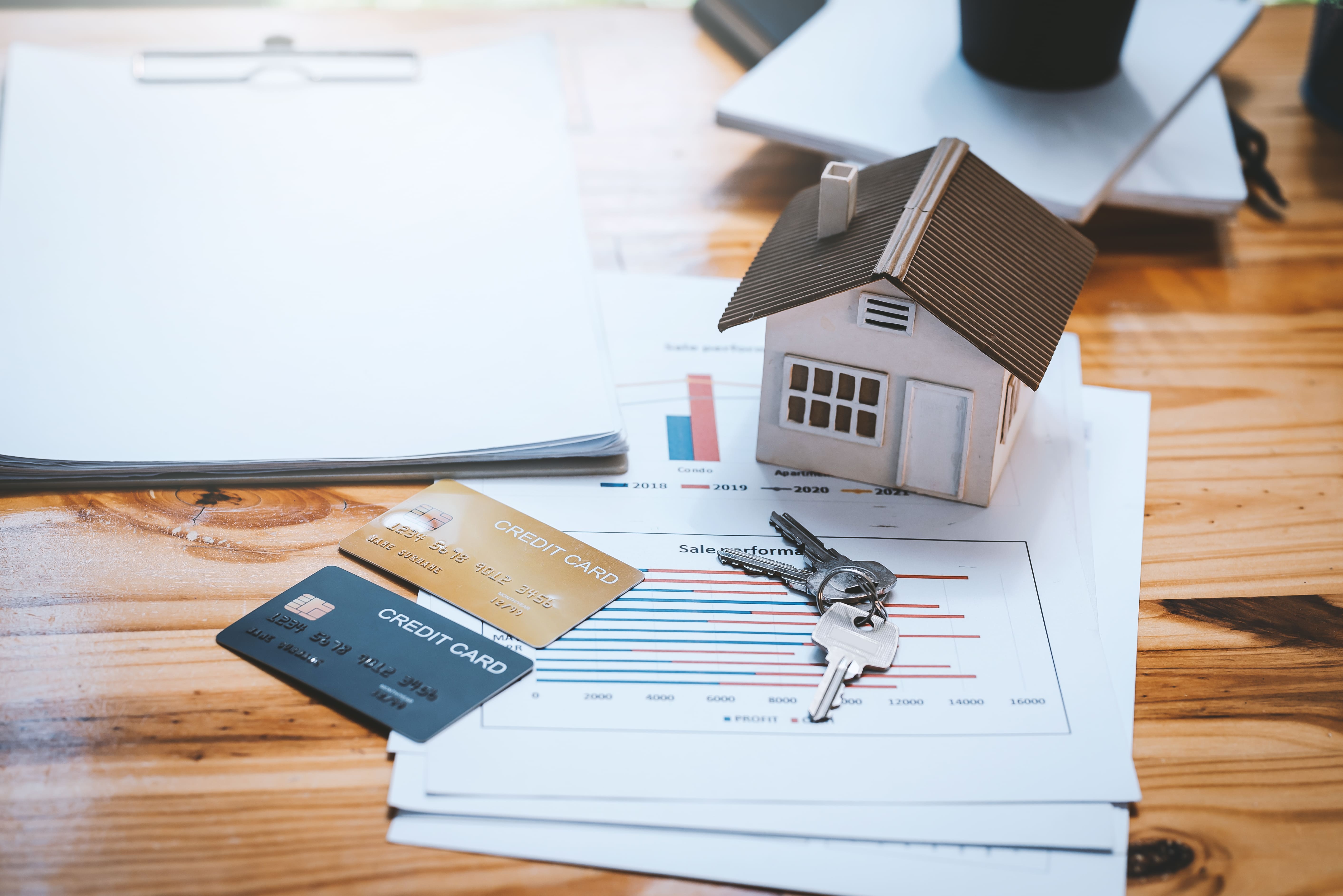 House model with credit cards and charts representing financial planning
