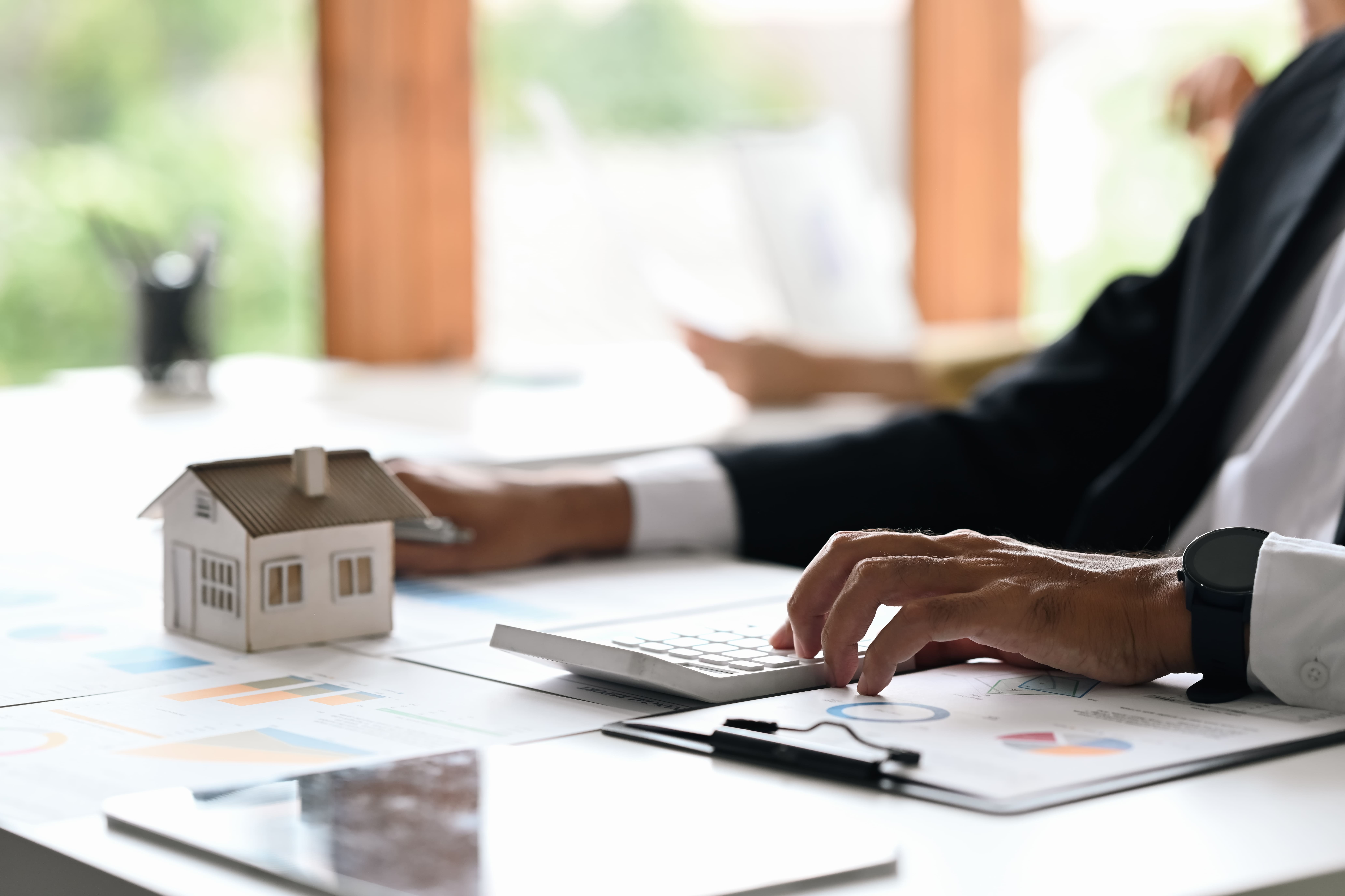 Financial professional calculating real estate returns with a house model