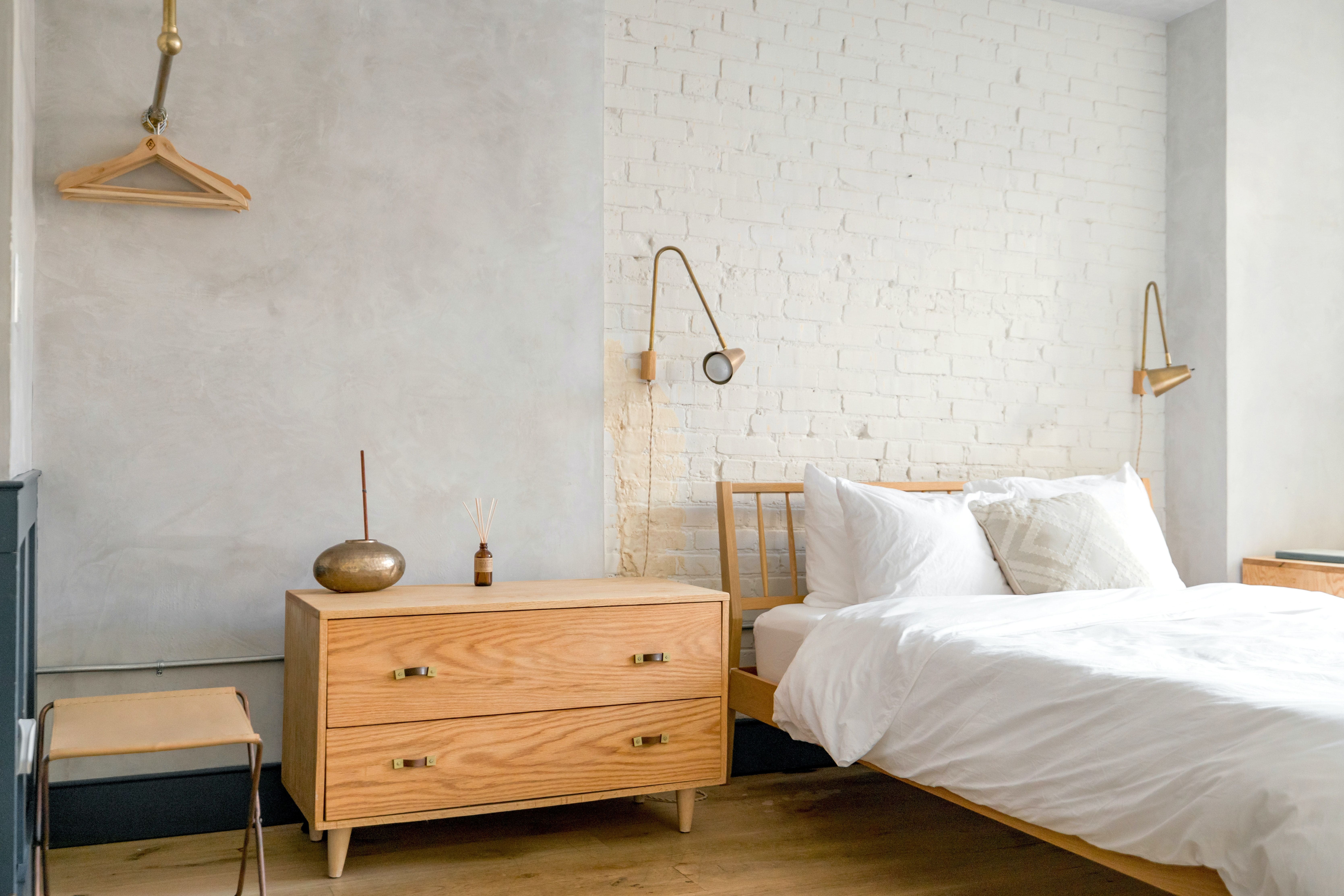 Minimalist STR bedroom with white brick wall and warm wooden furniture