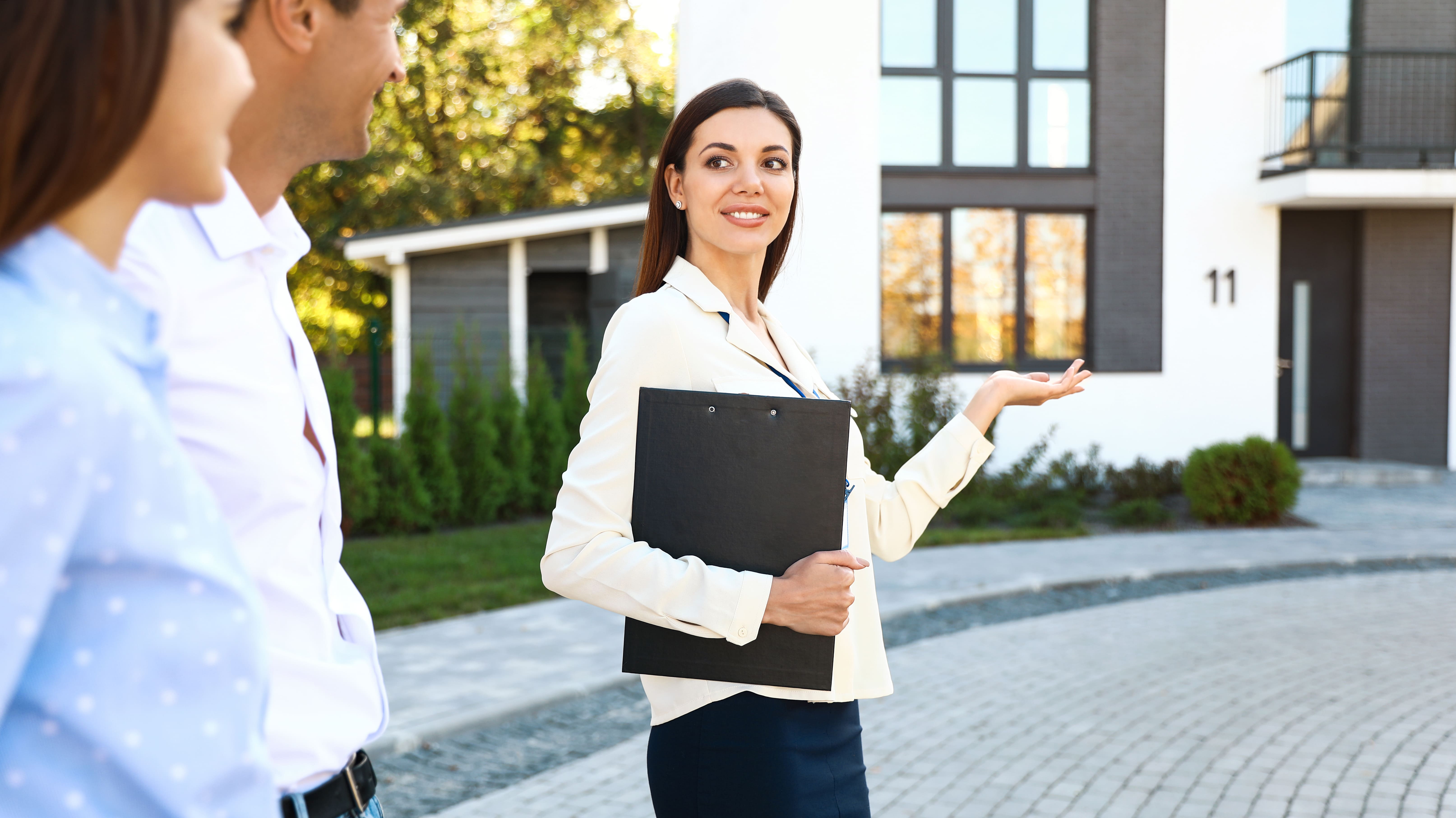 Agent showing and explaining a property to prospective buyers outdoors