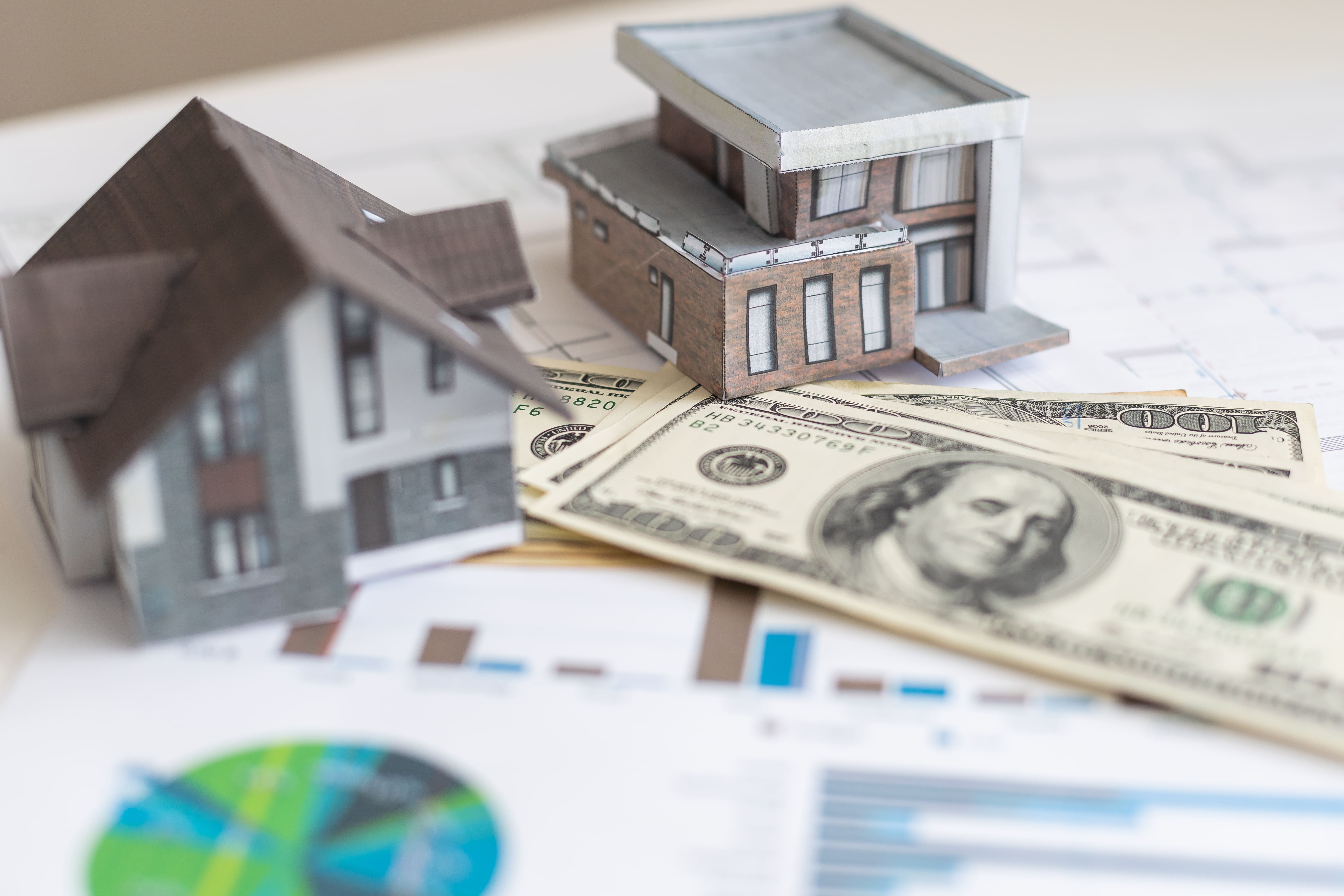 Property models on dollar bills with charts representing a real estate fund