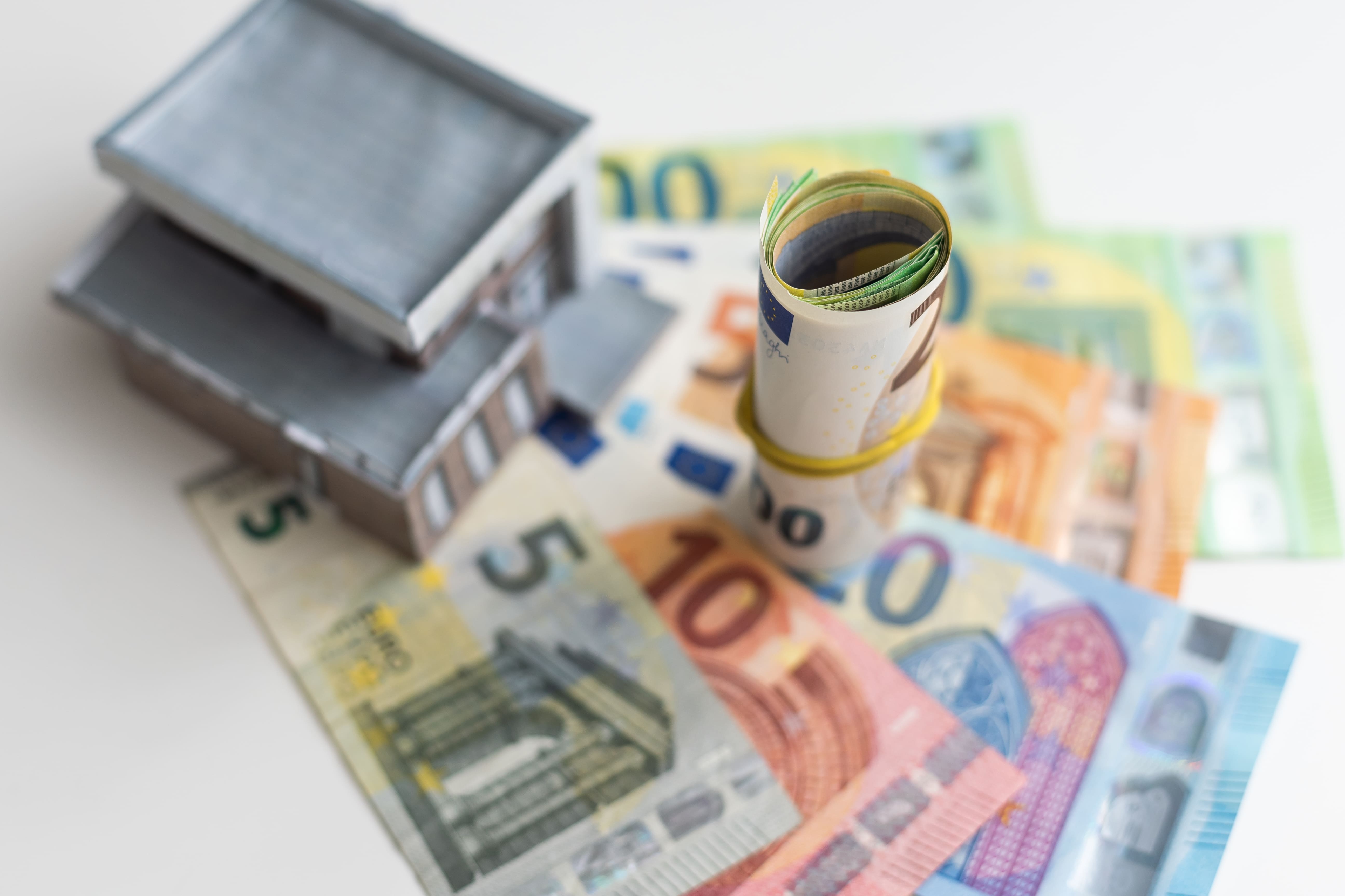 House model surrounded by rolled banknotes representing real estate capital