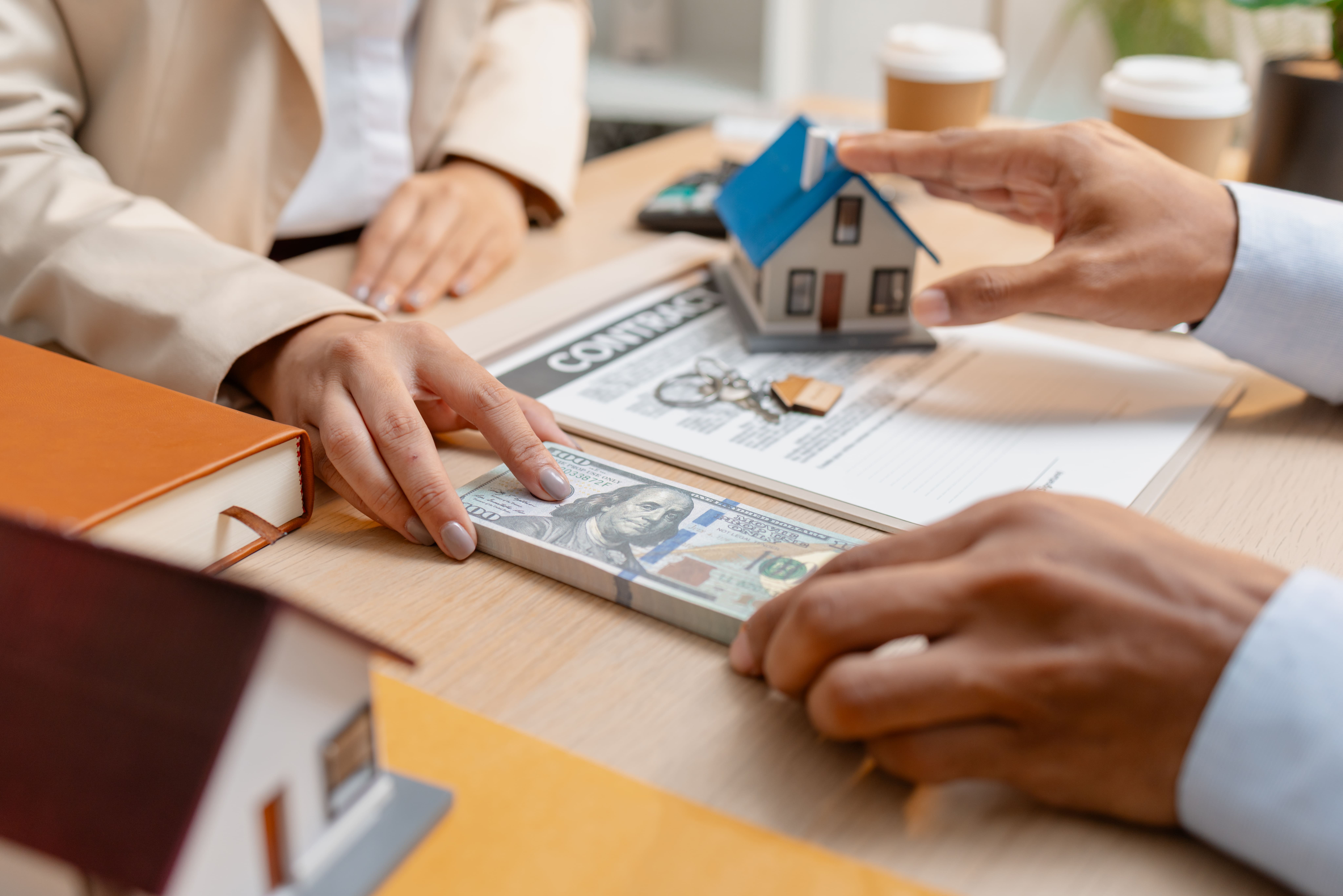 Cash and contracts exchanged at a real estate deal closing table