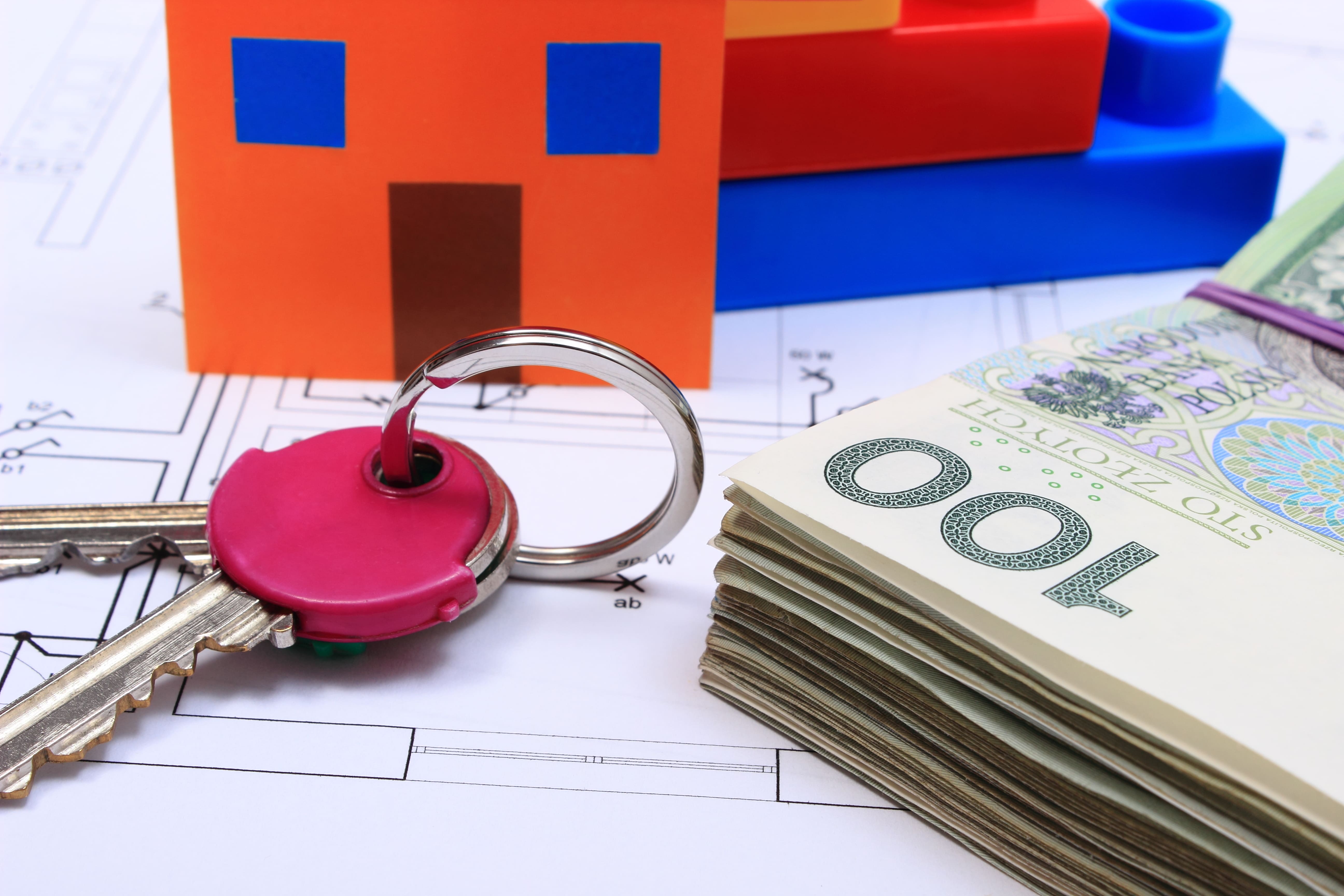 Keys, cash, and a house model on a blueprint representing a real estate deal