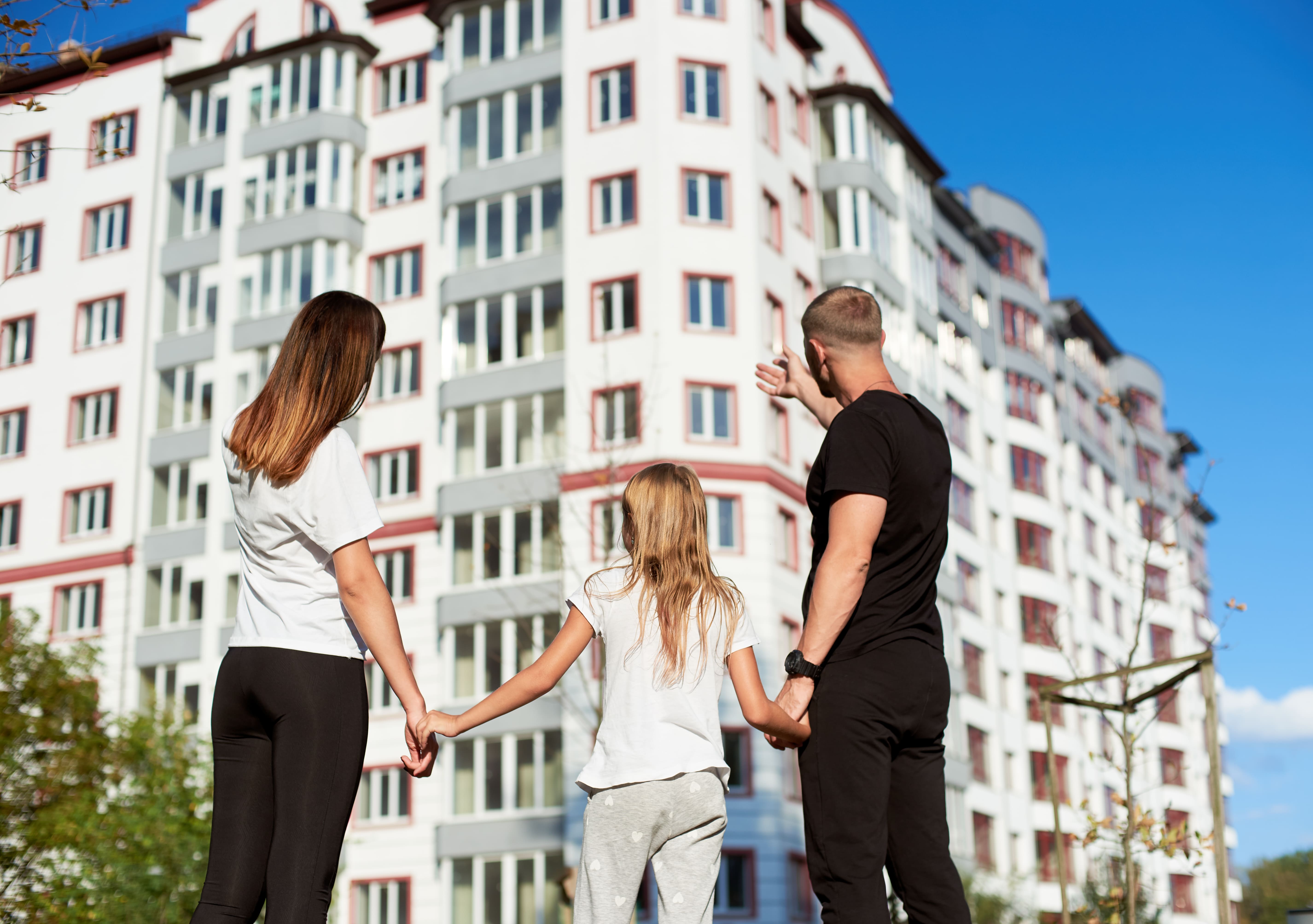 A family standing in front of a multifamily apartment building for rent
