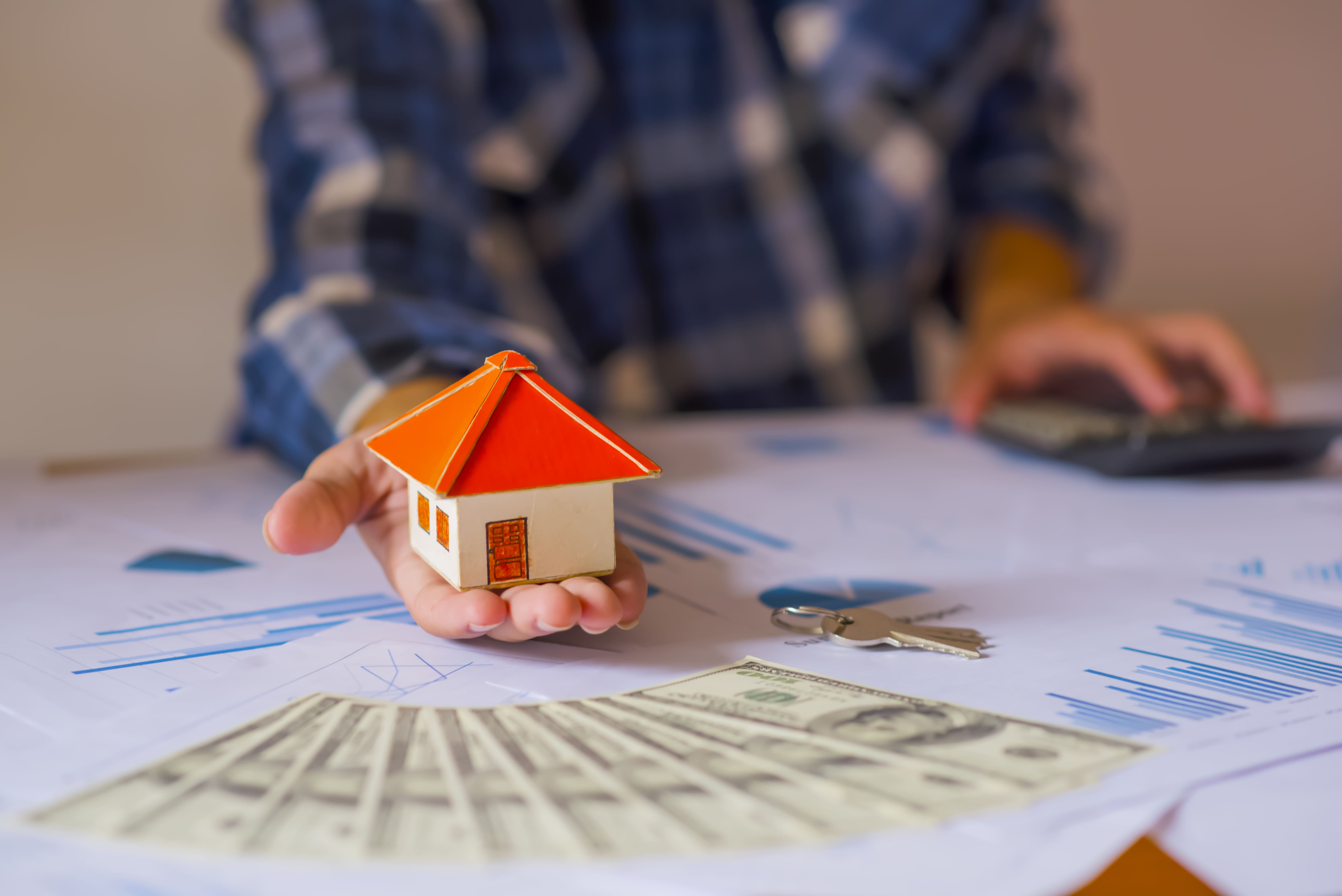 Investor holding a property model while engaged in financial planning