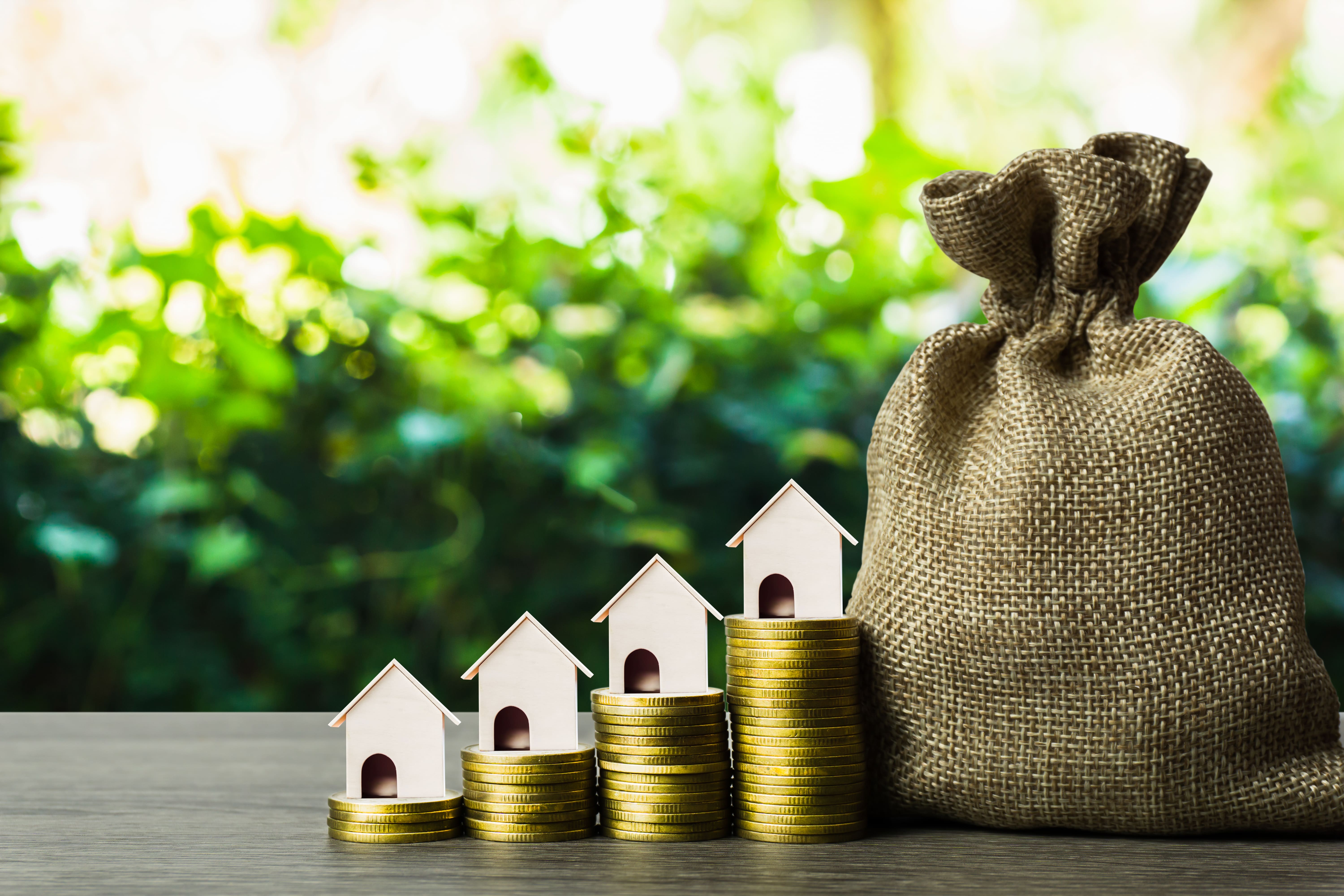 Houses on rising coin stacks representing real estate portfolio growth